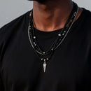Man wearing multiple necklaces with a focus on one featuring a triangular pendant, Obroi