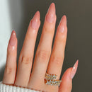 Close-up of a hand with long, manicured nails wearing two rings on a neutral background, Obroi