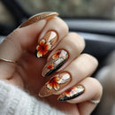 Hand with floral nail art in orange, black, and white on a blurred background, Obroi