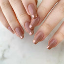 Close-up of hands with nude-colored nail polish on a light background, Obroi