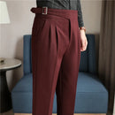 Maroon pants with a belt worn by a person, blurred background of a room.