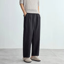Person wearing black wide-leg pants and a beige knit sweater on a light gray background, Obroi