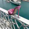 Pink high-heeled shoe on a railing with a marina background, Obroi