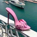 Pink high-heeled shoe with floral design on a railing by a marina, Obroi