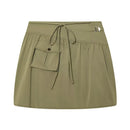 An olive green mini skirt with a drawstring waist, a side pocket with a snap button, and a small silver metal accent on the hip, shown against a plain white background, Obroi
