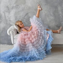 Young girl in a pink and blue dress sitting on a couch against a gray , Obroi textured wall.
