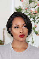 Woman with a short black hairstyle wearing a gray sweater in front of a floral background, Obroi