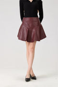 Person wearing a black top and maroon leather skirt on a white background, Obroi