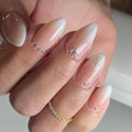 Close-up of a hand with almond-shaped nails featuring a gradient design and glitter accents, Obroi