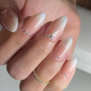Close-up of a hand with almond-shaped nails featuring a gradient design and glitter accents, Obroi