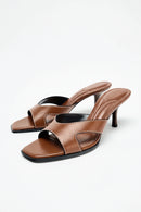 Pair of brown high-heeled sandals on a white background, Obroi