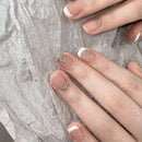 Close-up of hands with decorative nail art on a textured gray background, Obroi