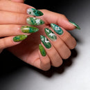 Hand with green floral nail art on a neutral background, Obroi