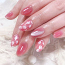 Close-up of hands with pink floral nail design on a soft white background, Obroi