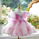 Pink and white dress on a mannequin with a blurred floral background, Obroi