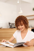 Woman reading a magazine in a kitchen setting, Obroi