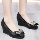 Black wedge shoes with decorative bows on a light gray background, Obroi