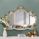 Decorative mirror with ornate frame on a shelf against a green wall, featuring 'Obroi' branding.