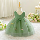 Green dress with floral embroidery on a mannequin against a soft floral background, Obroi