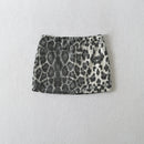 A mini skirt with a black and white leopard print pattern, made of textured fabric or sequins, shown flat against a light gray textured background, Obroi