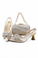A coordinated women's formal accessories set on a white background: two pointed-toe slingback heels in champagne satin with large jeweled bow embellishments, a matching rhinestone-covered clutch with a pearl-beaded handle, and a 'Obroi' logo watermark in the top left corner.