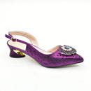 Purple glittery high heel shoe with a decorative brooch on a white background, Obroi