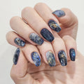Hand with galaxy-themed nail art on a light background, Obroi
