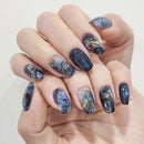 Hand with galaxy-themed nail art on a light background, Obroi