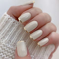 Hand with beige nail polish and gold accents on a white background, Obroi
