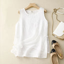 White sleeveless top on a hanger with shoes and a handbag on a beige surface, Obroi