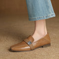 Brown leather loafer shoe worn with light blue jeans on a textured brown surface, Obroi