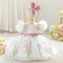 White dress with pink floral patterns and a matching headband on a mannequin against a light background.obroi
