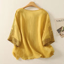 Yellow blouse with embroidered sleeves on a wooden hanger against a white background, Obroi