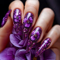 Nails with purple floral design and glitter on a dark background, Obroi