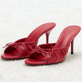 Red high-heeled shoes with bow details on a white background, Obroi