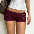Maroon shorts with a gold ring detail worn by a person, on a plain background, Obroi