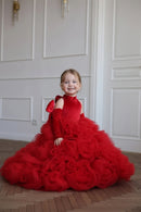 Young girl in a red dress standing in a room with white paneled walls, Obroi