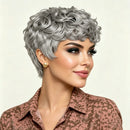 Woman with styled gray hair wearing a patterned brown jacket on a beige background, Obroi