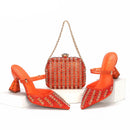 Orange high-heeled shoes with crystal embellishments and a matching handbag on a white background, Obroi