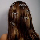 Hair accessories with bow designs on a person's head against a neutral background, Obroi