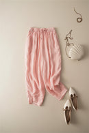 Pink pants on a beige surface with white shoes and decorative items, Obroi