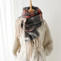 Plaid scarf with tassels draped over a white coat on a wooden stand against a white background, Obroi