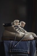 Pair of brown boots with black laces on a dark background, Obroi