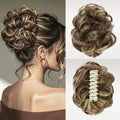 A hairpiece/wig extension shown in three views: worn in a bun on a woman's head, isolated on the right, and the underside with a white claw clip visible. The hair has a warm brown base with blonde highlights, Obroi