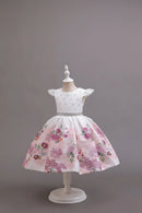 A toddler girl's formal dress displayed on a white mannequin dress form against a solid gray studio background. The dress features a white sleeveless bodice with small rhinestone embellishments, fluttery cap sleeves, a beaded waistband, and a full flared skirt with a pink and purple floral pattern, Obroi