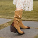 Brown suede knee-high boots with a worn-in look on a person wearing a white lace dress, Obroi
