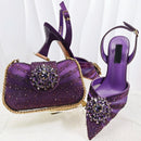 Purple high-heeled shoes and matching handbag with embellishments on a white background, Obroi