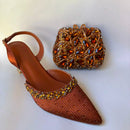 Brown embellished high-heeled shoe and matching handbag on a white background, Obroi