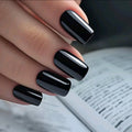Close-up of a hand with black nail polish holding an open book, Obroi