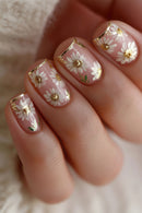 Nails with floral design and gold accents on a neutral background, Obroi